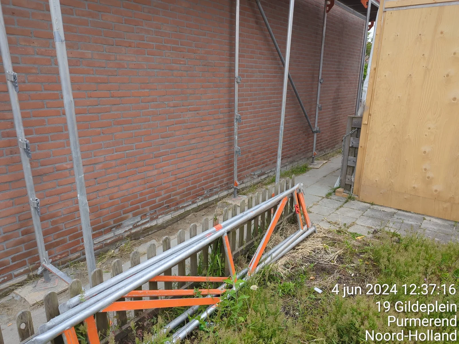 Bakstenen gevel voor renovatie, met steigerwerk en versleten voegen